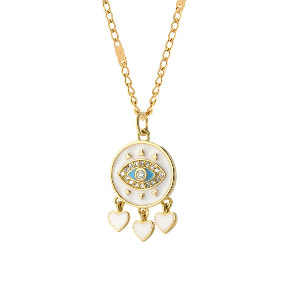 A gold necklace featuring a circular pendant with an intricate “evil eye” design in the center, surrounded by small triangular accents. The pendant is adorned with three dangling heart charms and hangs on a delicate gold chain. The design combines protective symbolism with elegant detailing.